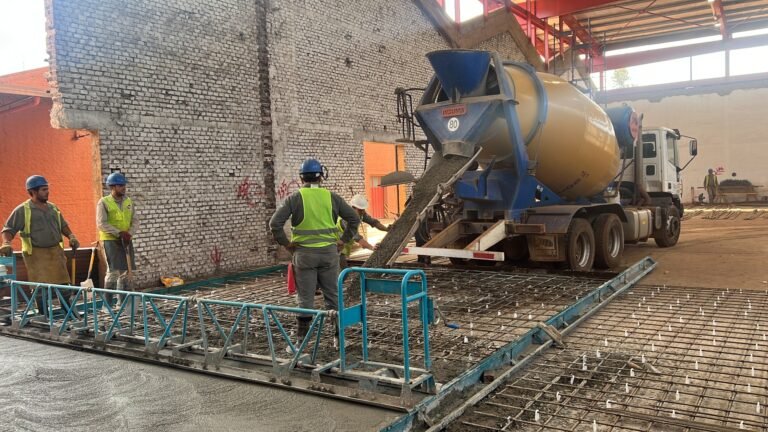 Camión descargando hormigón con personal trabajando sobre el piso